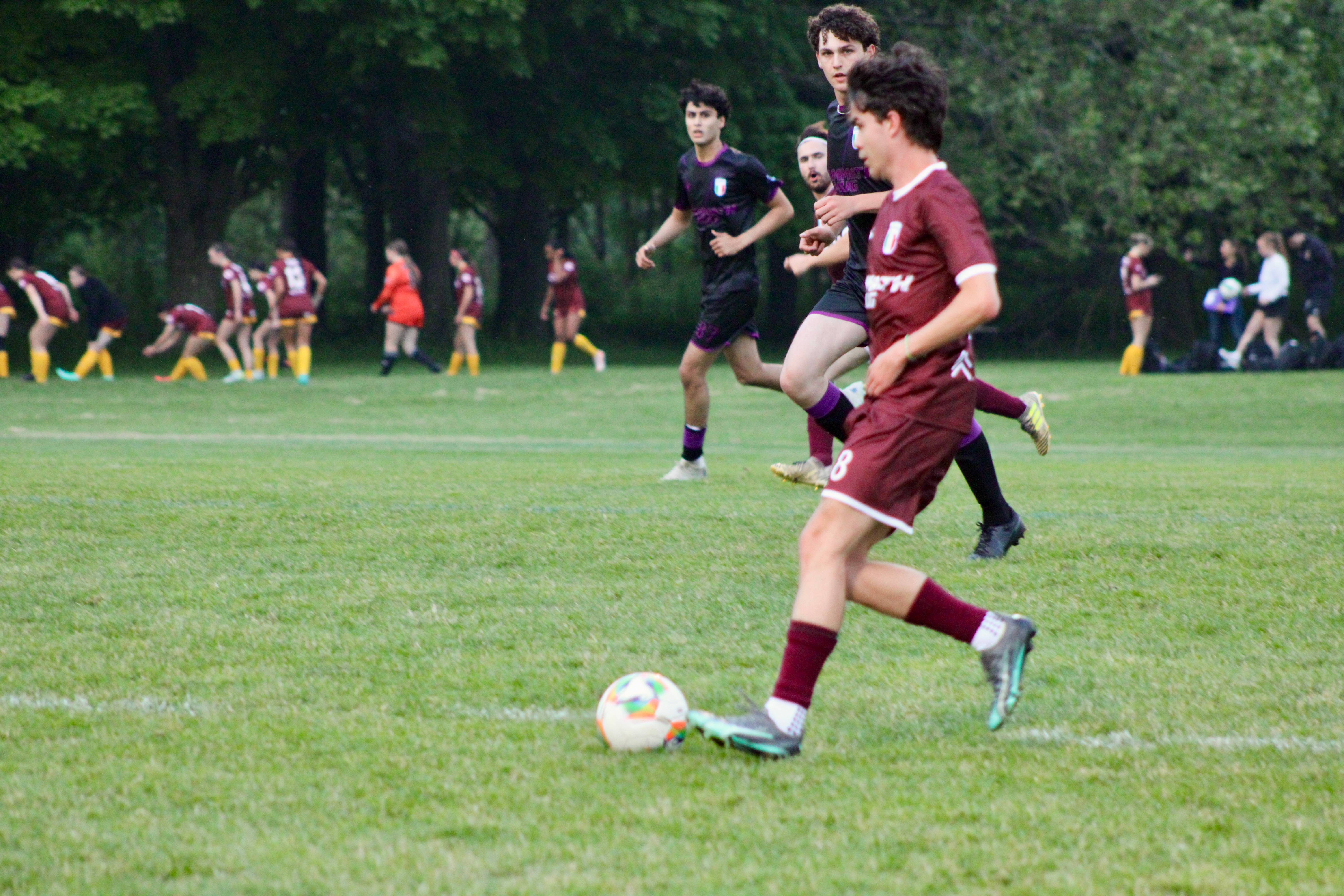 Buringa FC players in maroon jerseys during match action, player dribbling while being pursued