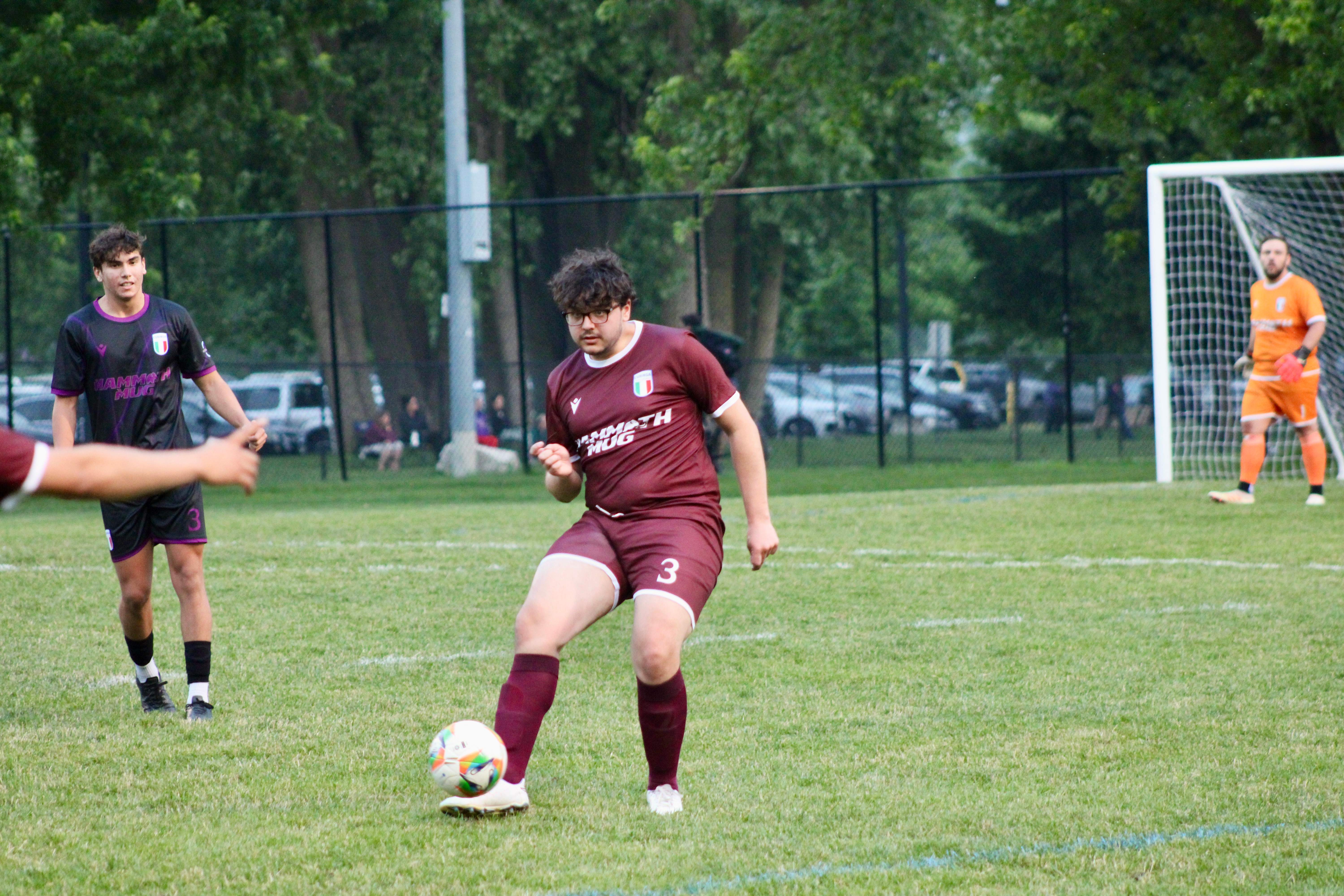 Buringa FC player (#3) with glasses dribbling the ball during outdoor match