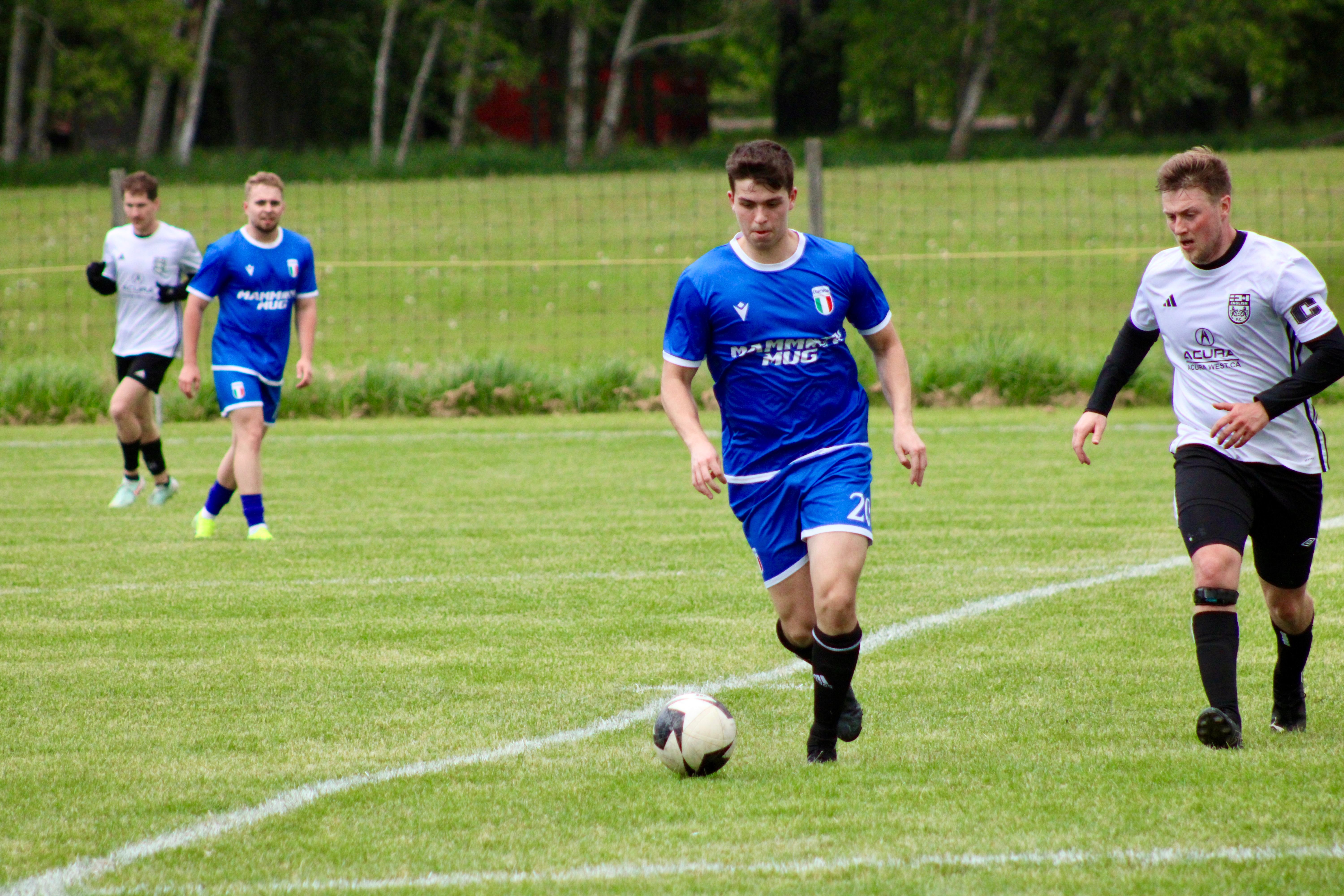 Curinga FC player (#21) dribbling past opponent during outdoor match