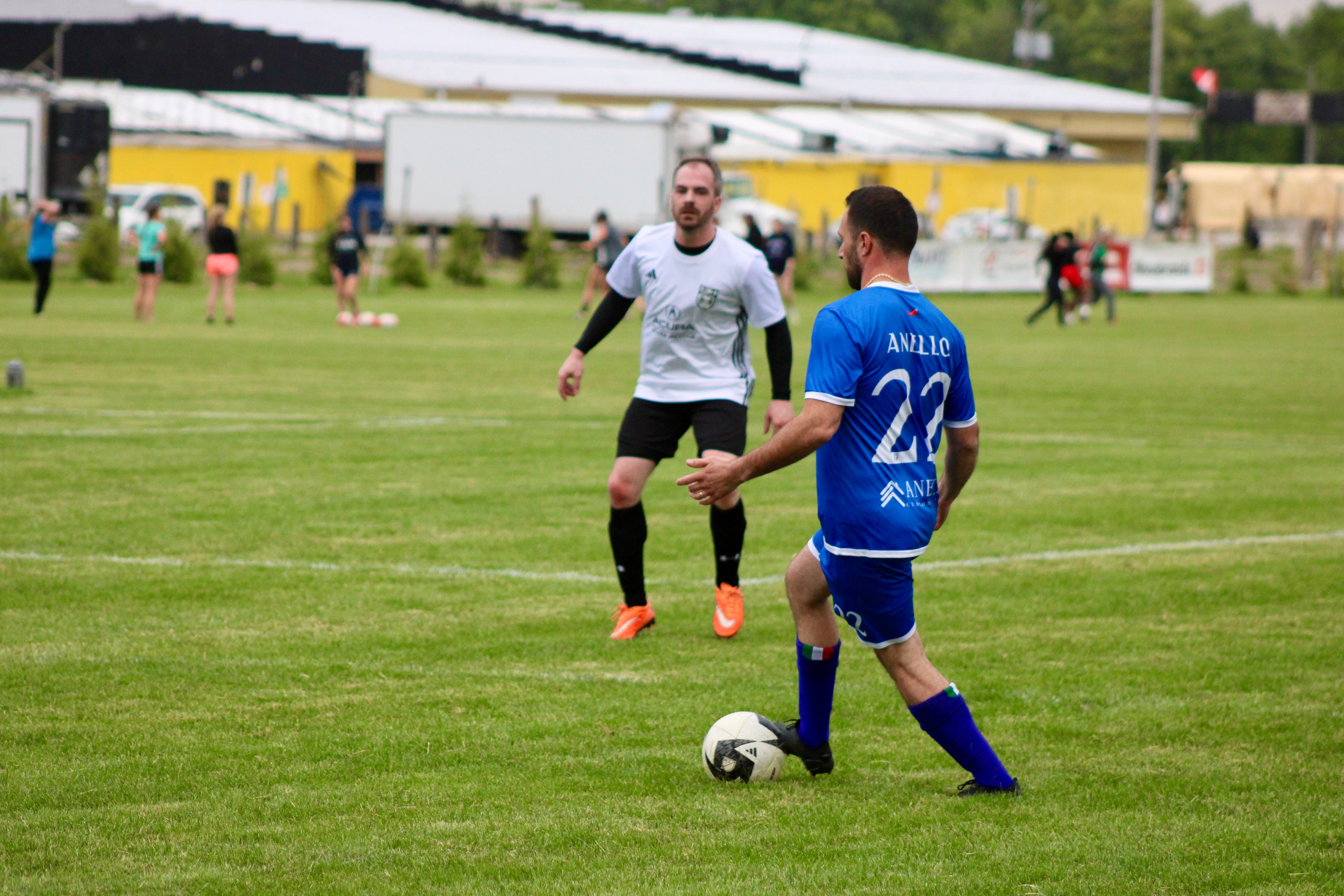 Anello (#22) controlling the ball against opponent in outdoor match
