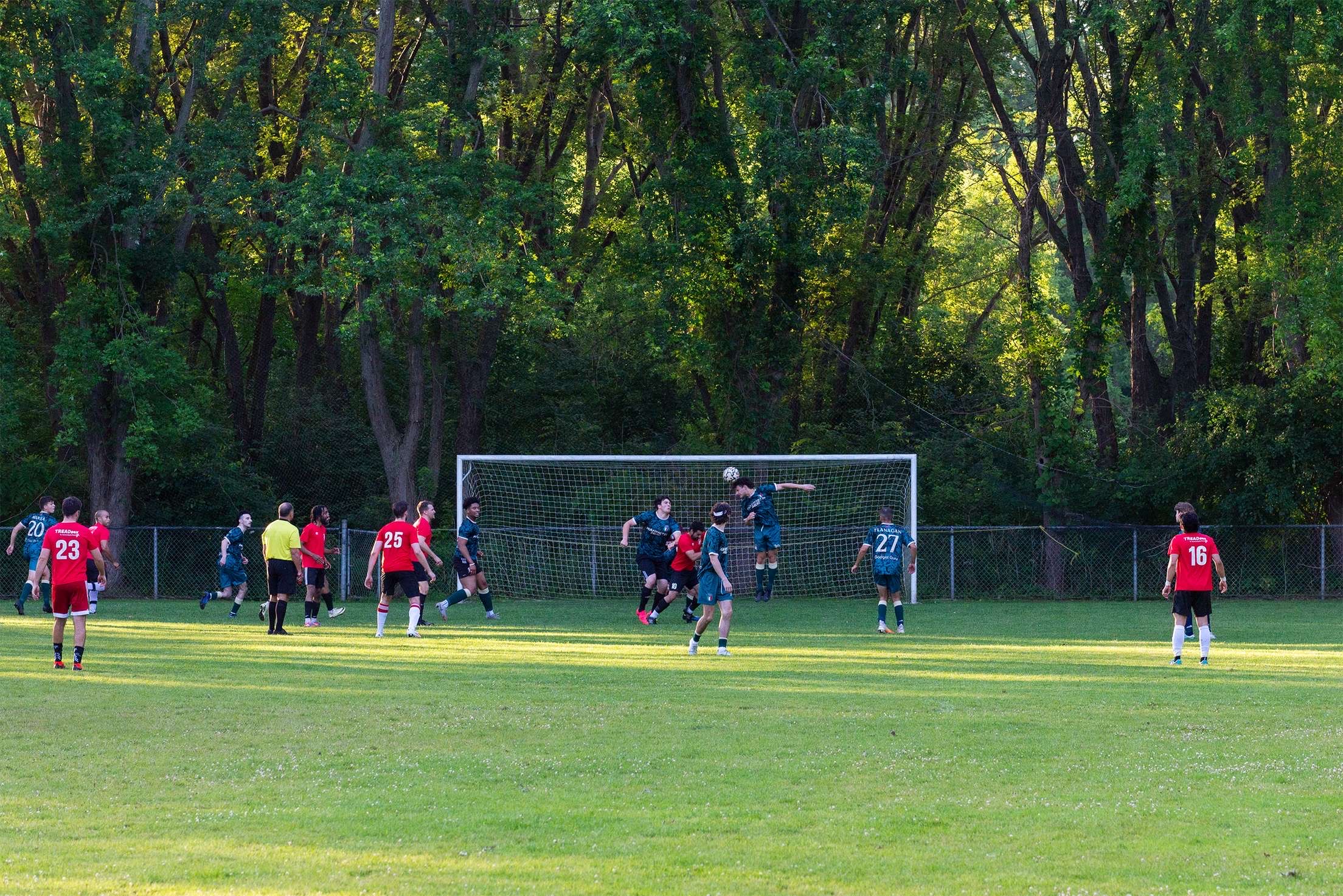 Curinga FC players competing for a header against opponents in red
